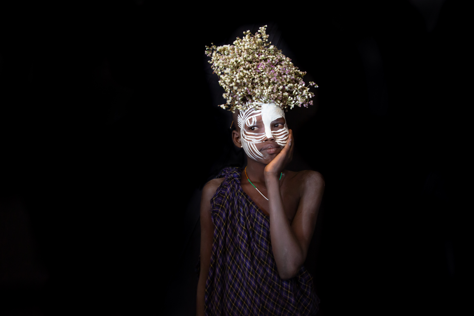 A young Suri girl decorated with face painting and flowers