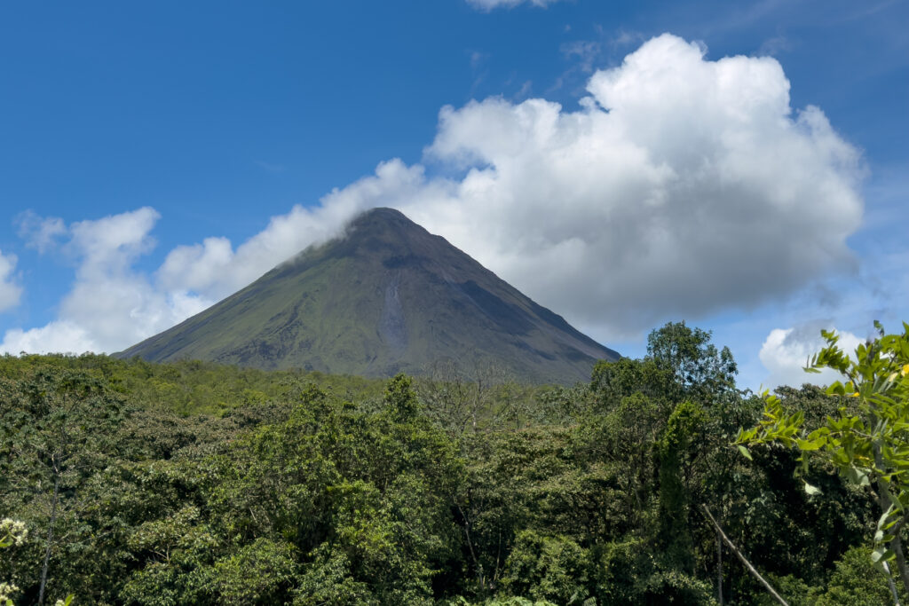 A glimpse of Arenal Volcano's summit on a sunny day. Still active, there is always a plume of smoke mingling with the clouds at its peak (image by Inger Vandyke)