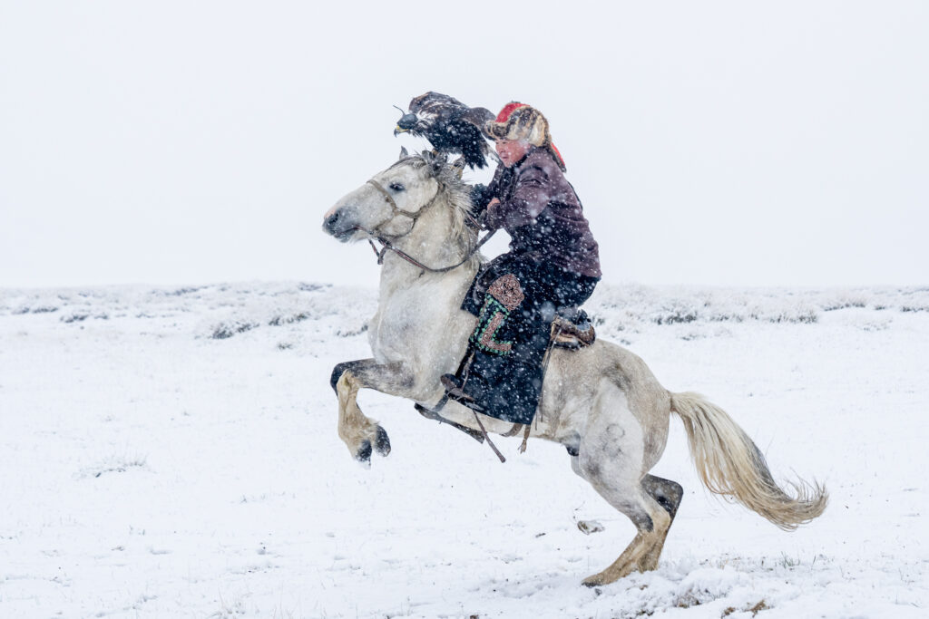 An eagle hunter racing his horse through a snow storm (image by Inger Vandyke)